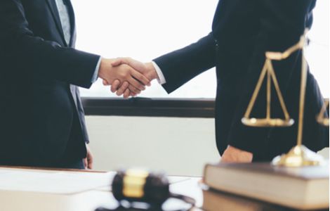 Consulenza legale per aziende negli Stati Uniti - L'immagine raffigura due professionisti in abiti formali che si stringono la mano in un ufficio, simbolo di accordi commerciali e partnership. In primo piano, una bilancia della giustizia e un martelletto da giudice rappresentano il supporto legale. Us Company Advisor offre assistenza giuridica per aziende italiane che vogliono operare nel mercato USA, garantendo conformità normativa e tutela legale.