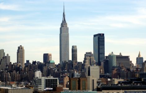 Skyline di New York con l'Empire State Building al centro, circondato da grattacieli e edifici iconici. Vista urbana chiara con cielo sereno, rappresentando il cuore finanziario e imprenditoriale degli Stati Uniti.