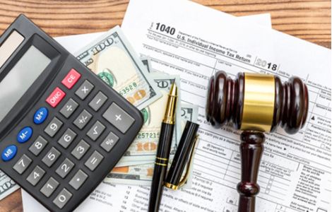 Gestione fiscale e conformità legale per aziende negli USA - L'immagine raffigura documenti fiscali ufficiali statunitensi (U.S. Individual Income Tax Return 1040), una calcolatrice, banconote da 100 dollari, penne e un martelletto da giudice su una scrivania in legno. Questa composizione rappresenta la gestione delle tasse, la conformità legale e il supporto amministrativo. Us Company Advisor assiste le aziende italiane nella fiscalità, apertura di conti bancari e conformità alle normative negli Stati Uniti.