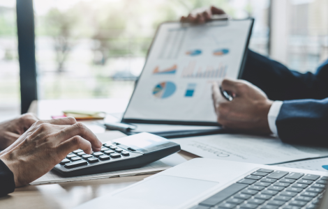 Ottimizzazione aziendale con holding, fondazioni non profit e stati offshore-friendly negli USA - L'immagine mostra un incontro di business con due professionisti in giacca che analizzano grafici finanziari e utilizzano una calcolatrice per pianificare strategie di ottimizzazione fiscale e strutture societarie. Us Company Advisor assiste le aziende italiane nella creazione di holding, strutture offshore e fondazioni non profit per operare in modo efficiente e conforme nel mercato statunitense.